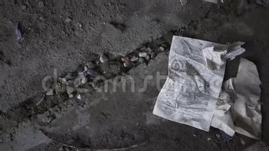 一座废弃的建筑的混凝土地板上躺着一本皱巴巴的书页。 酒杯掉在地上，